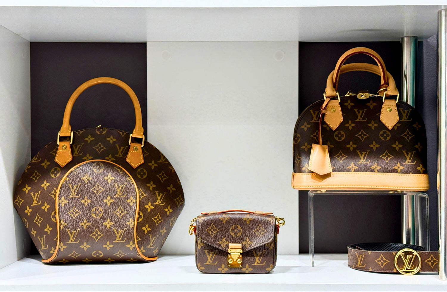 Louis Vuitton handbags displayed on a shelf with a black background